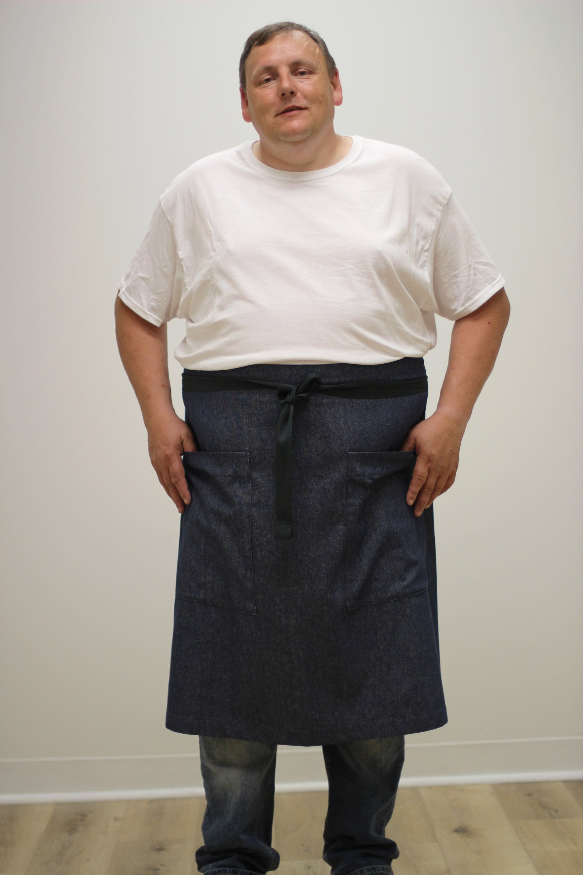 Long Half Apron in Denim _ front view with hands on pockets