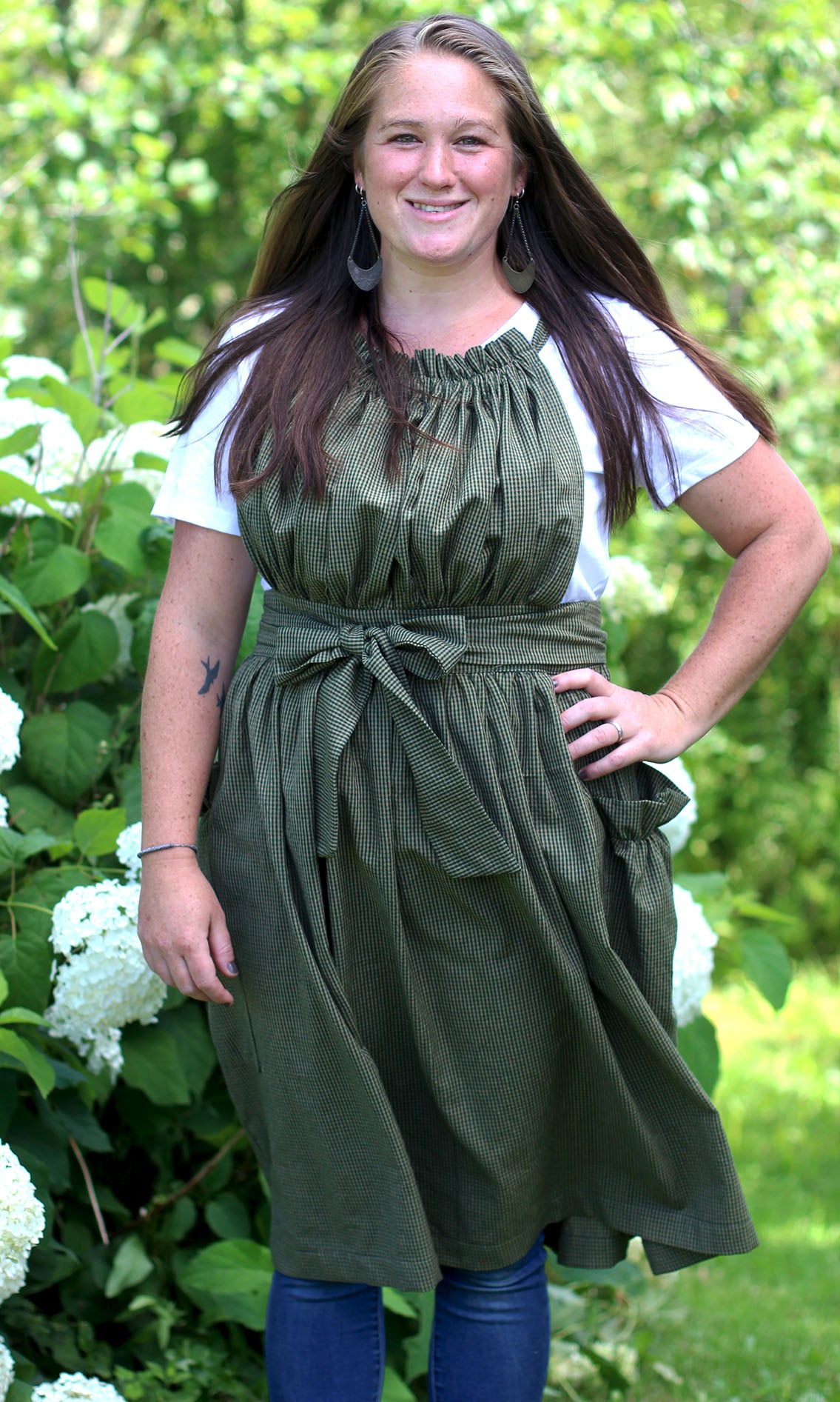 XS-5X Gathered Bib Apron in Tiniest Plaid, 100% Cotton Homespun - Front View with bow tied in front amongst the hydrangeas.