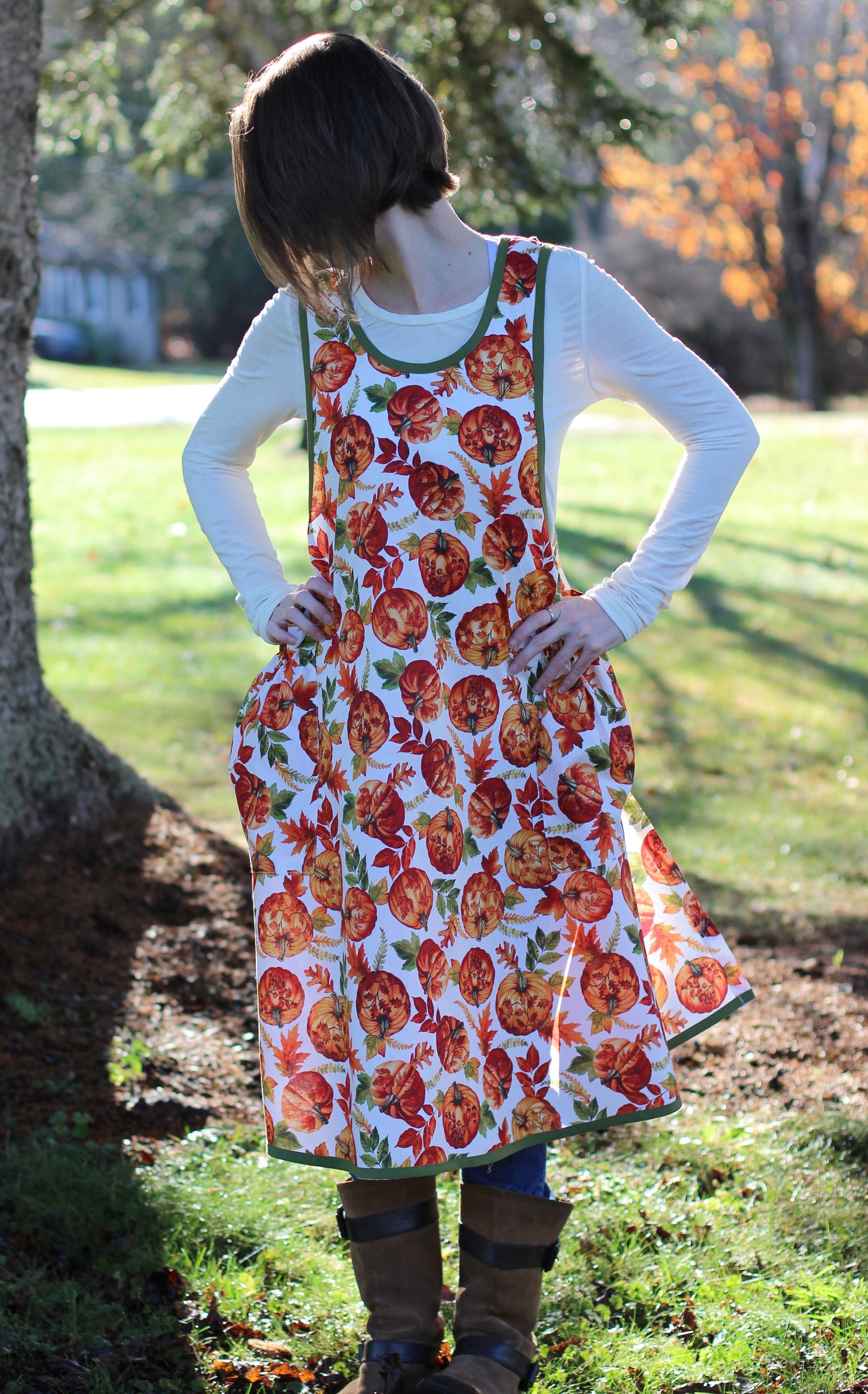 No Ties Apron in a Pumpkin Print - Front view with model wearing brown boots.