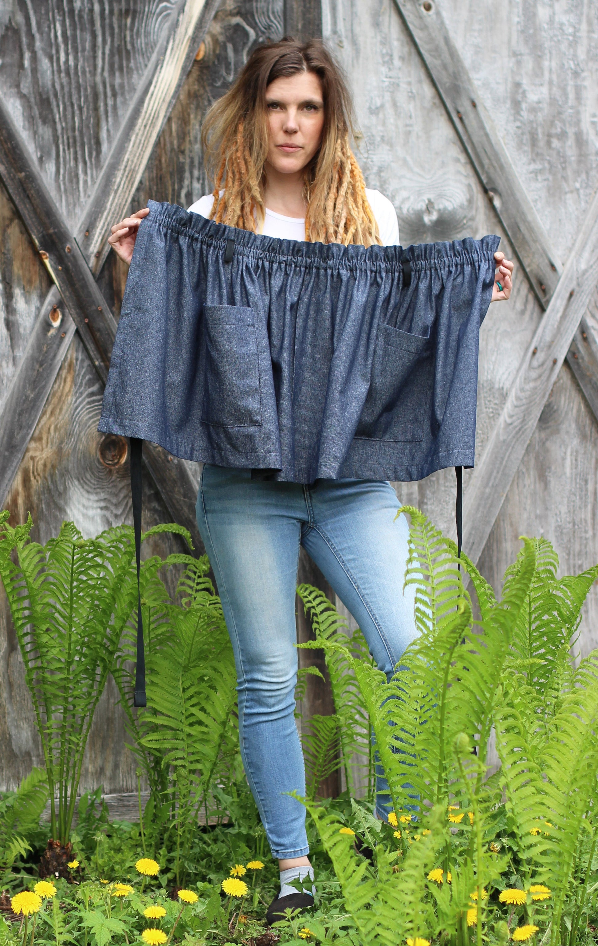Half Apron in Denim, model holds the apron up for a wide view.