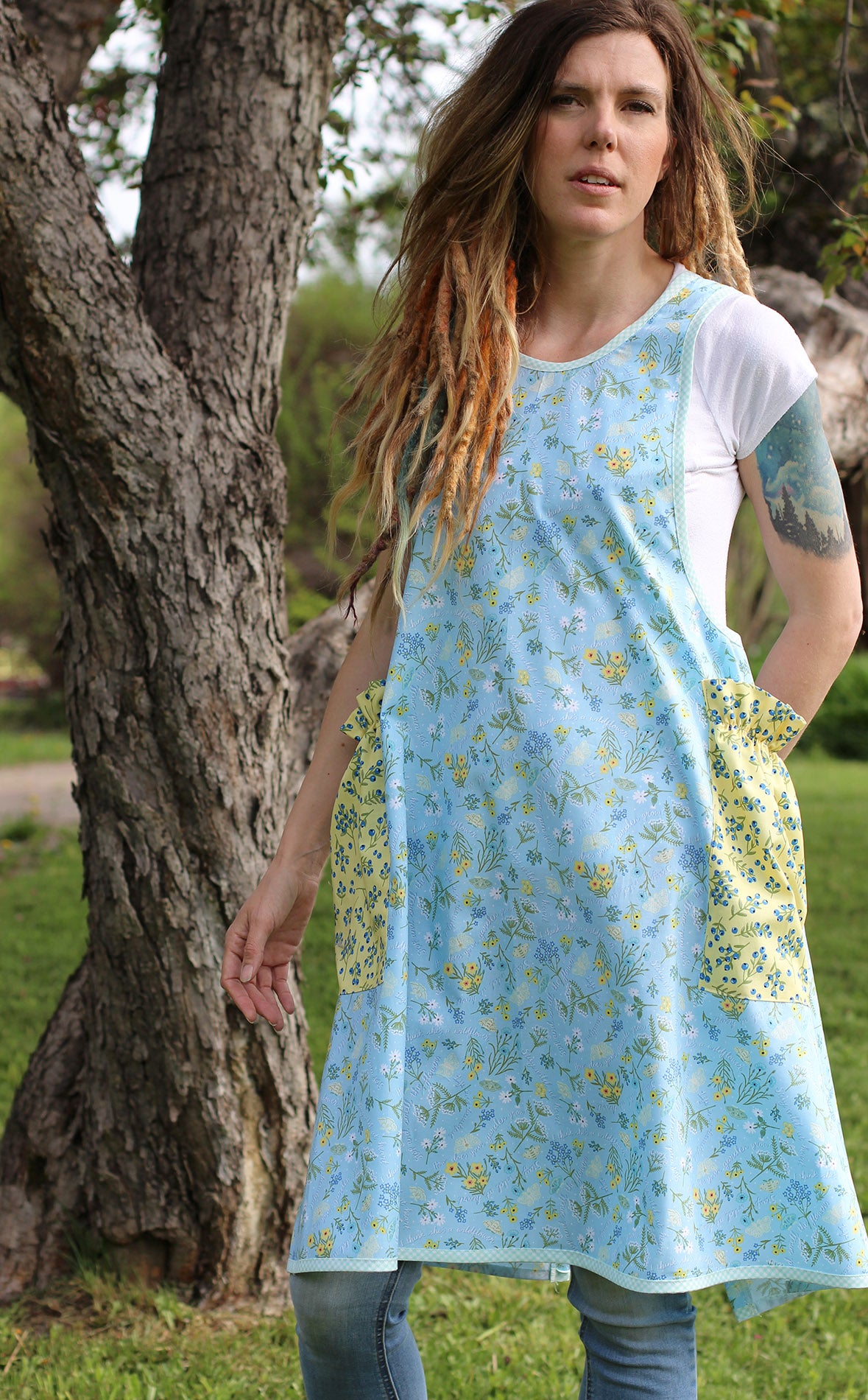 No Tie Apron in Blue Floral with Yellow Pockets - Front View with Model looking into the camera.