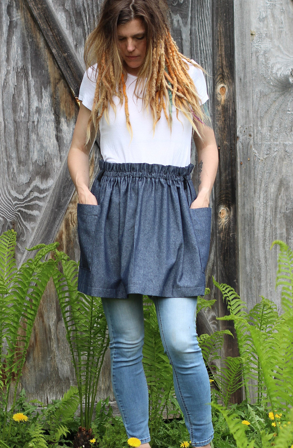 Half Apron in Denim with the models hands in the pockets.