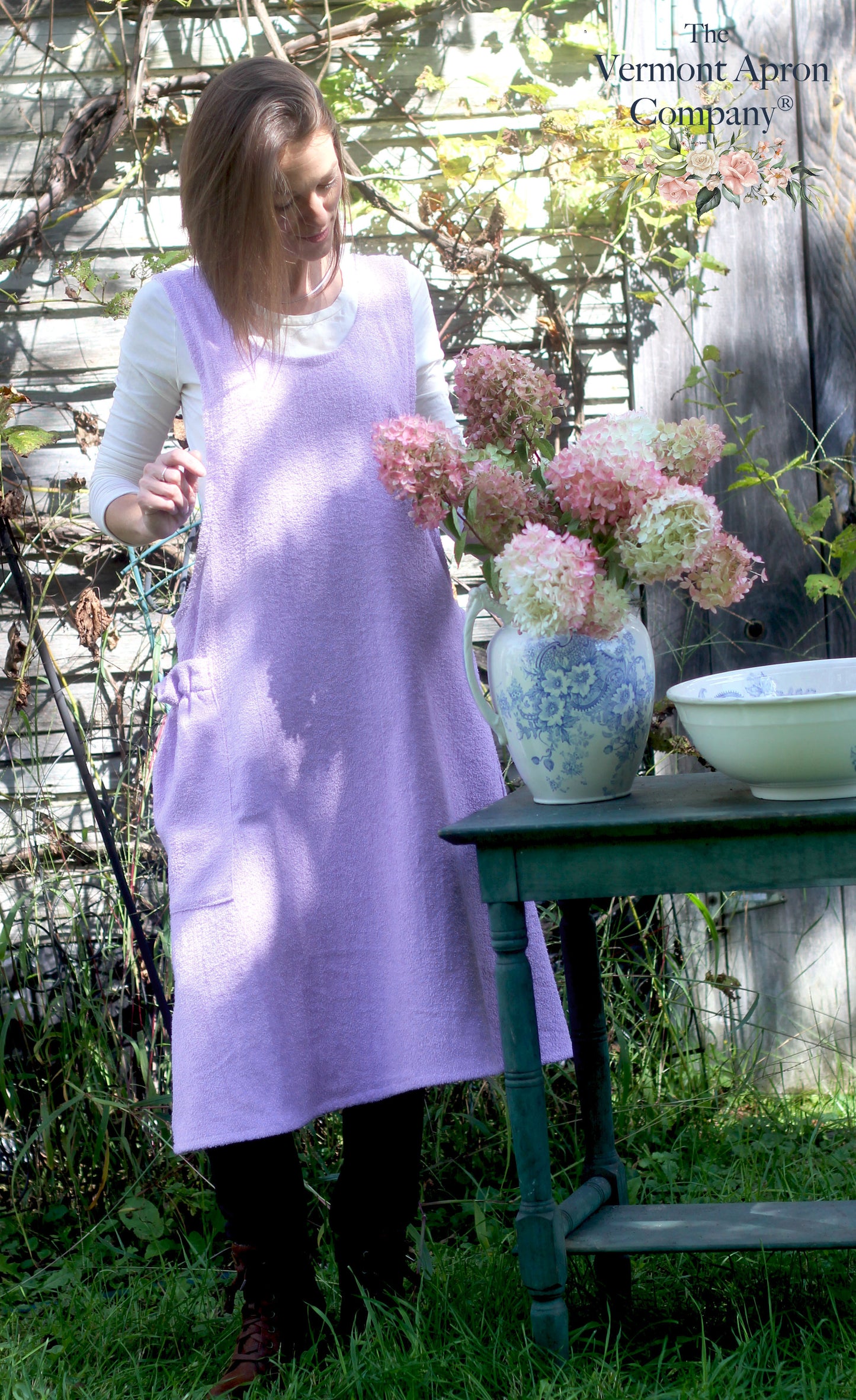 XS-5X Lilac Terry Apron - No Tie Crossback Apron - Model is arranging flowers.
