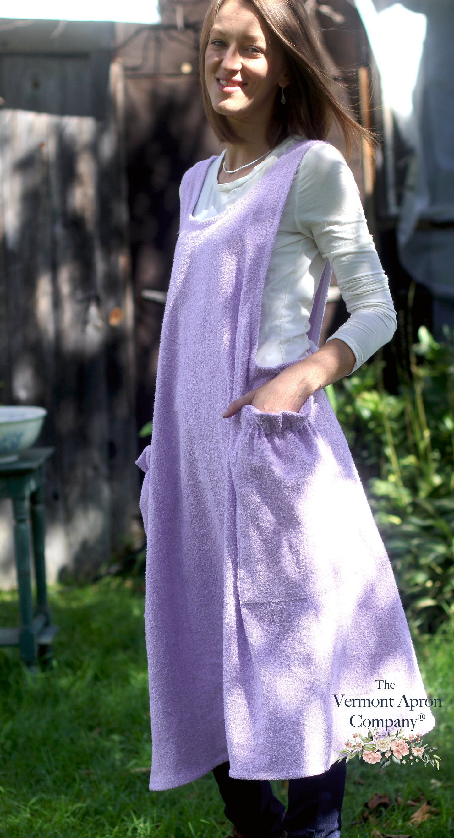 XS-5X Lilac Terry Apron - No Tie Crossback Apron - The Model is smiling into the camera offering a side view of the apron.