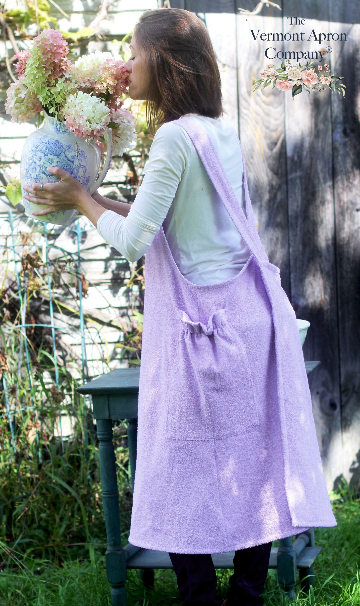 XS-5X Lilac Terry Apron - No Tie Crossback Apron - The Model is smelling the flowers.